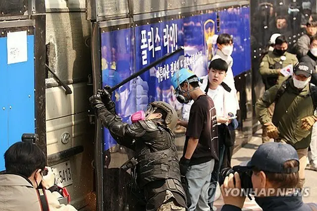 警察のバスの窓を割る男＝４日、ソウル（聯合ニュース）