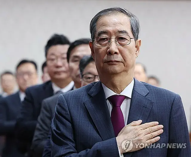 政府ソウル庁舎で開かれた閣議で国旗に敬礼する韓悳洙首相＝１４日、ソウル（聯合ニュース）