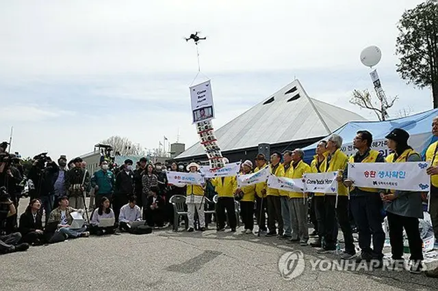 ビラ散布のパフォーマンスを行う「戦後拉北者被害家族連合会」の関係者＝２３日、坡州（聯合ニュース）
