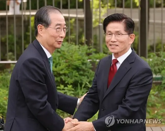 握手する韓氏（左）と金氏＝８日、ソウル（聯合ニュース）