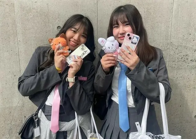 ９日、会場でグッズを手にポーズを取る来場者＝（聯合ニュース）