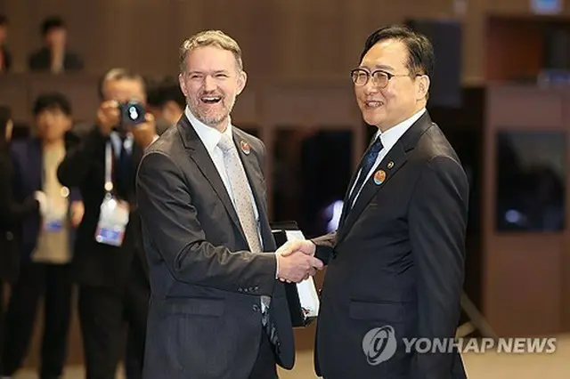 握手する韓国産業通商資源部の鄭仁教・通商交渉本部長（右）と米ＵＳＴＲのグリア代表＝１５日、西帰浦（聯合ニュース）