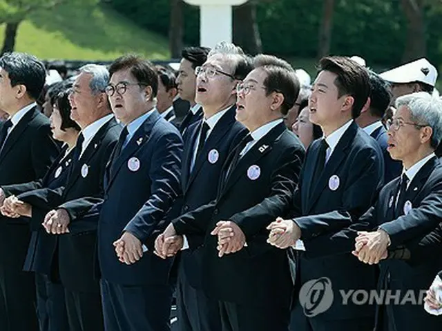 記念式典で手をつないで合唱する李在明氏（右から４人目）、李俊錫氏（同３人目）、「民主労働党」候補の権英国（クォン・ヨングク）代表（同２人目）の大統領選３候補＝１８日、光州（聯合ニュース）
