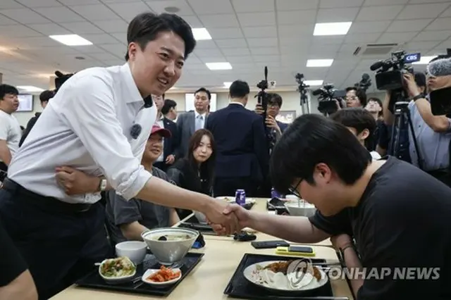 仁川市内の大学の学生食堂で学生と握手する李俊錫氏＝２２日、仁川（聯合ニュース）