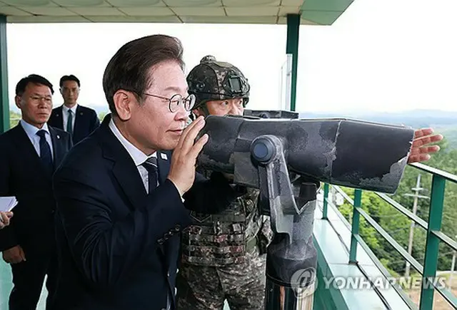 北朝鮮に近い京畿道漣川郡の陸軍前線部隊を訪問し、展望台から望遠鏡で北朝鮮側を見つめる李大統領＝１３日、漣川（聯合ニュース）