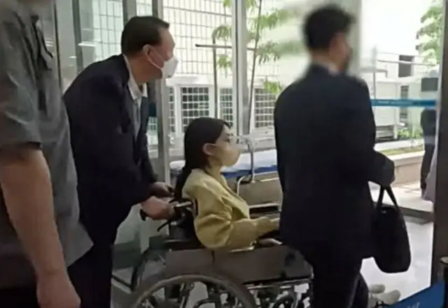 尹錫悦前大統領が押す車椅子に乗って退院する金建希夫人（写真＝SBS）