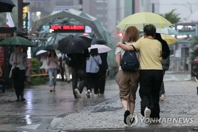 江南駅付近で傘を差して歩く人たち＝１６日、ソウル（聯合ニュース）