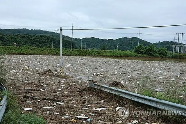大雨で押し流されてきたゴミやがれきで埋まった忠清南道公州市内の田畑＝１７日、公州（聯合ニュース）