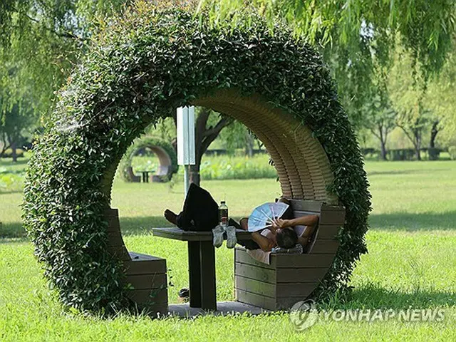 公園内の日陰にあるベンチで暑さをしのぐ市民＝２３日、釜山（聯合ニュース）
