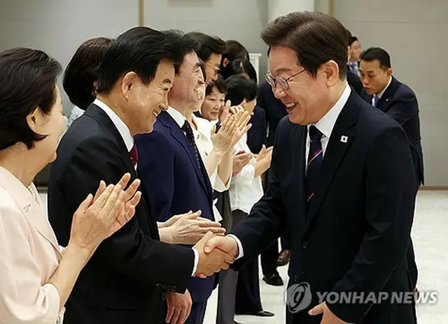 大統領室での任命状授与式で握手を交わす李大統領（右）と鄭東泳・統一部長官＝２８日、ソウル（聯合ニュース）