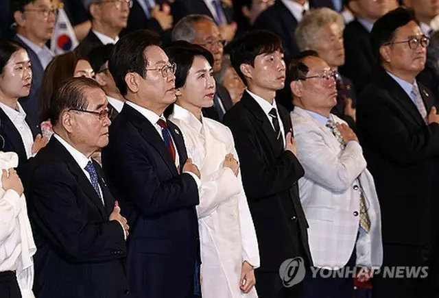 国旗に敬礼する李在明大統領夫妻＝１５日、ソウル（聯合ニュース）