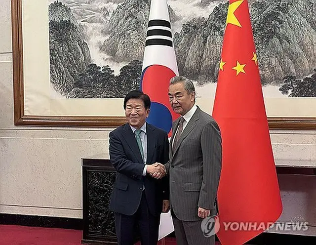 王氏（右）と握手を交わす朴特使団長（共同取材団）＝２４日、北京（聯合ニュース）≪転載・転用禁止≫